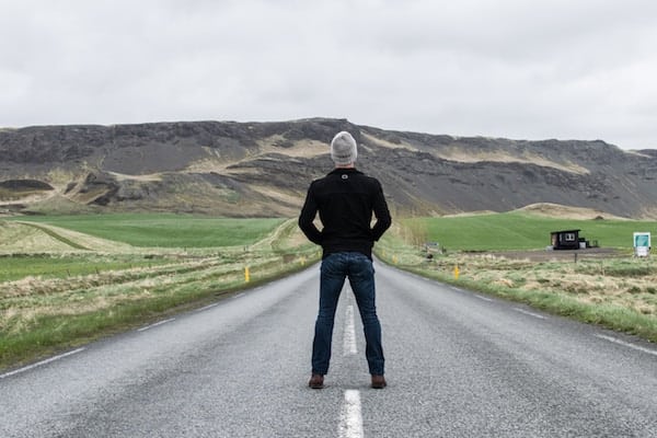 Man standing in the middle of the road, staring into the distance toward a mountain, ari monkarsh limit distractions